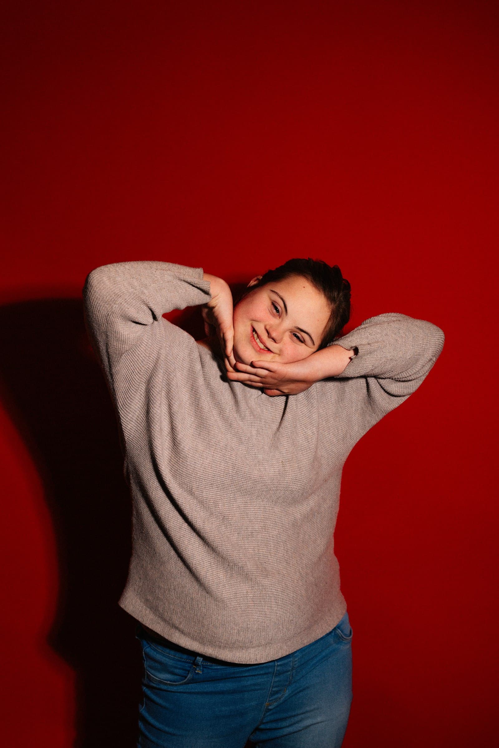 A young adult woman laughing, hands framing her face in a joyful expression