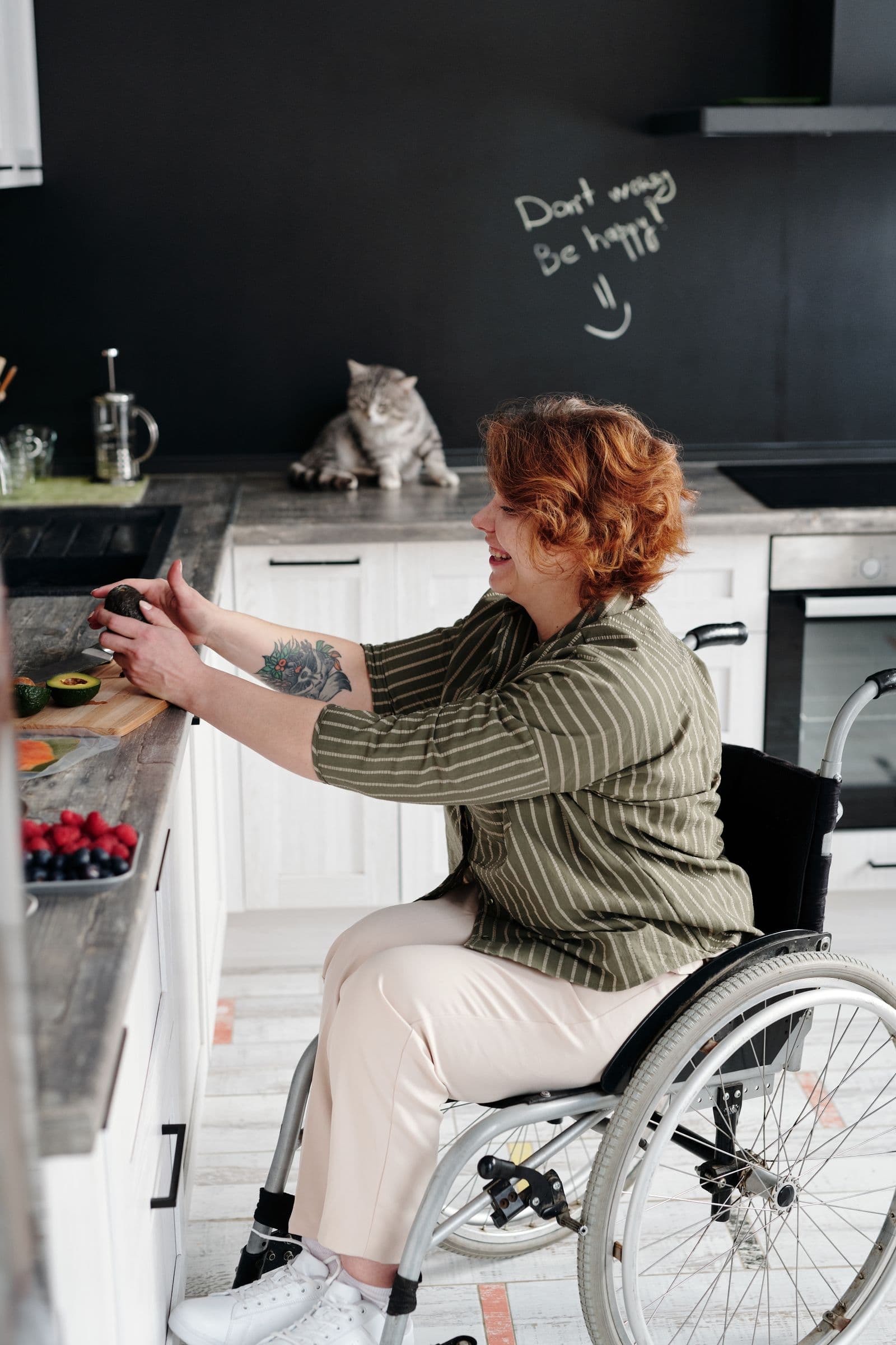 A smiling adult wheelchair user preparing a healthy meal in her kitchen